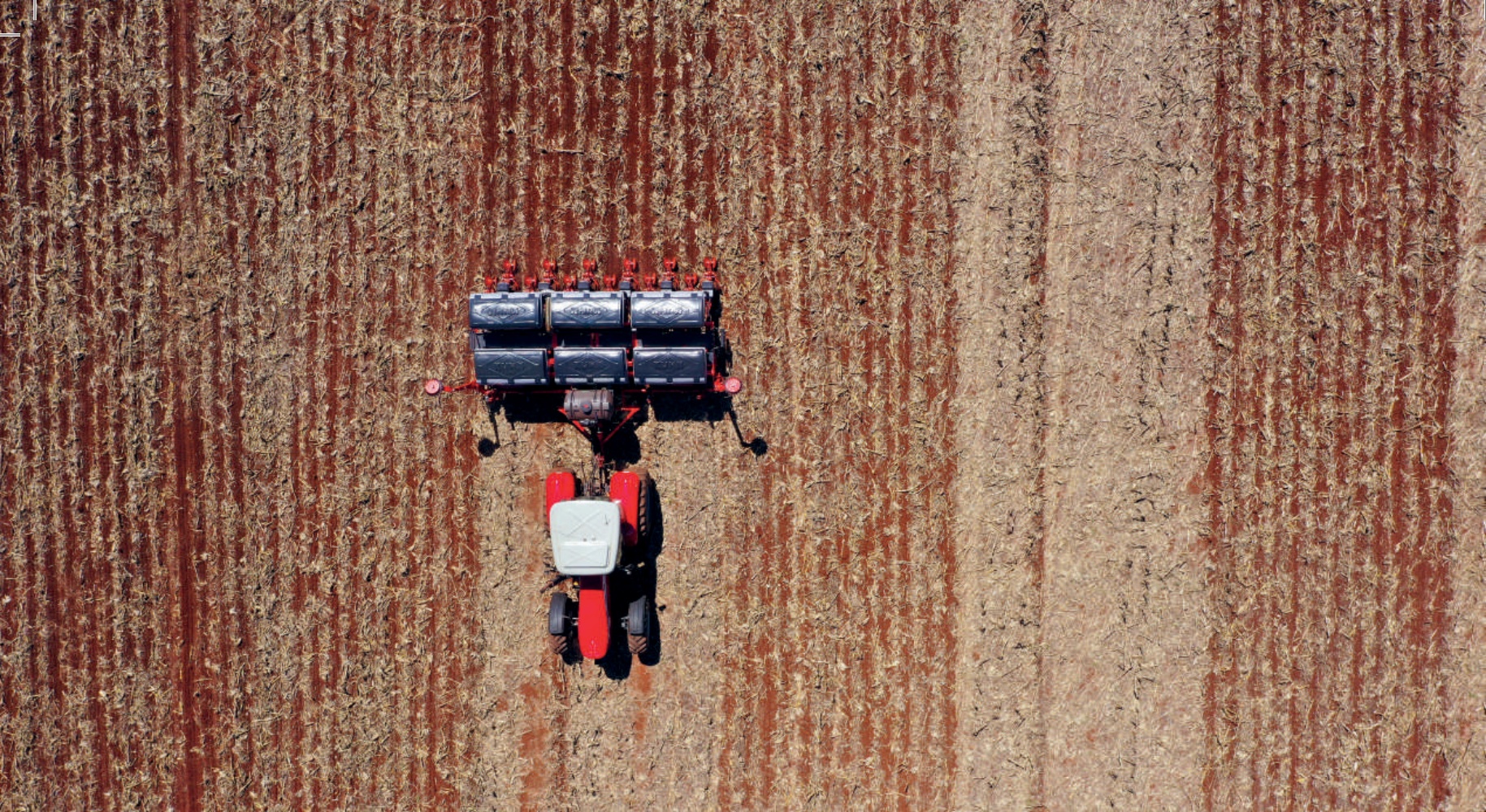 Vis&atilde;o a&eacute;rea de um trator plantando em uma lavoura de milho colhida