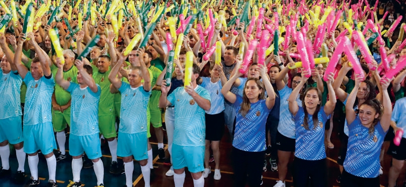 Equipe de cooperados comemorando em evento esportivo com bal&otilde;es coloridos
