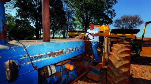 Carlos Chagas Ferreira ao lado de um trator azul