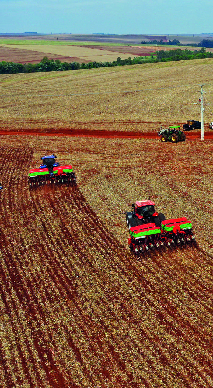 Vista a&eacute;rea de tratores realizando o plantio em campo arado.