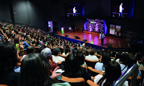 Palco do evento com plateia ao fundo.