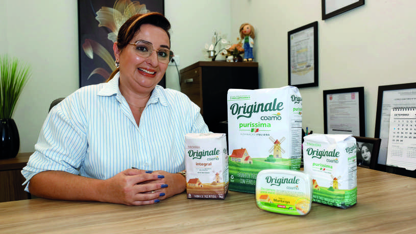 Fabiana Schimidt Doneda sentada em sua mesa de escrit&oacute;rio com produtos da linha Originale.