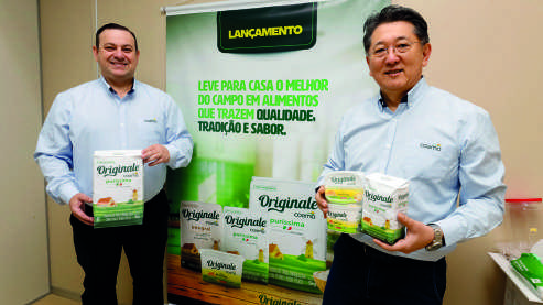 Marcio Munhoz e Edson Watanabe em frente a um banner da linha Originale.